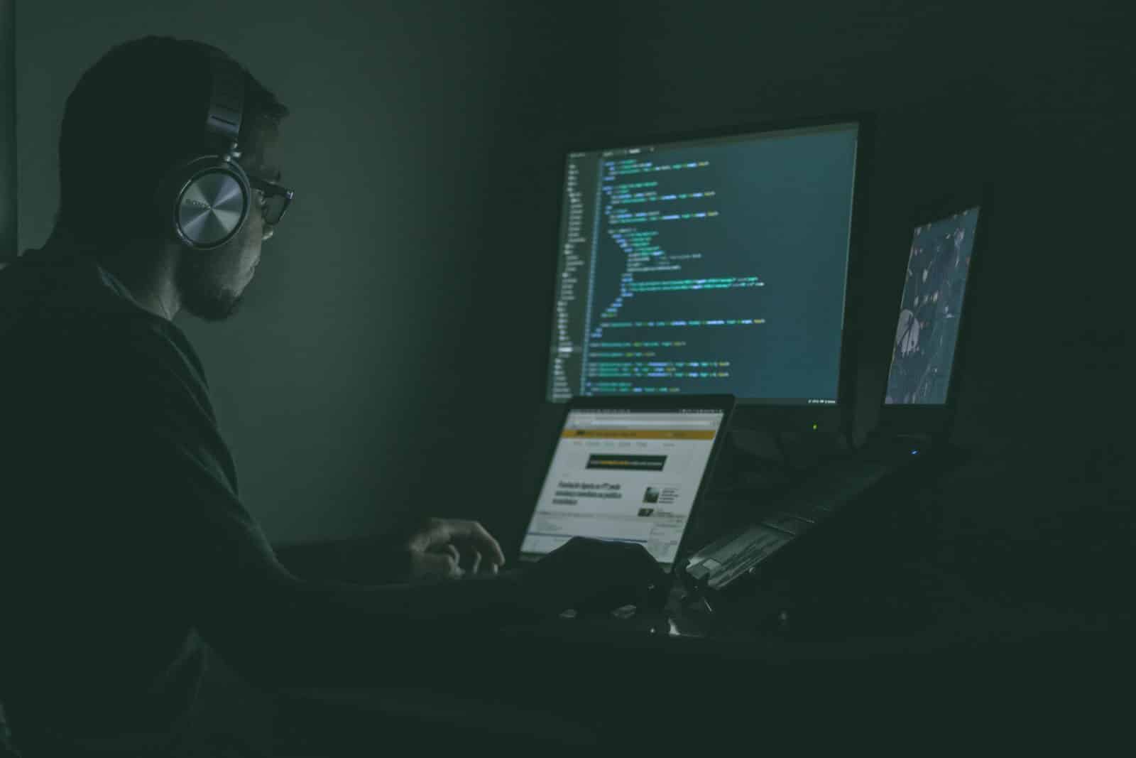 Un développeur au travail devant plusieurs écrans affichant du code